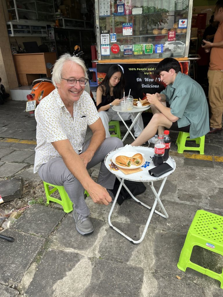 small table and chairs outside street vendor. Enjoying Banh Mi